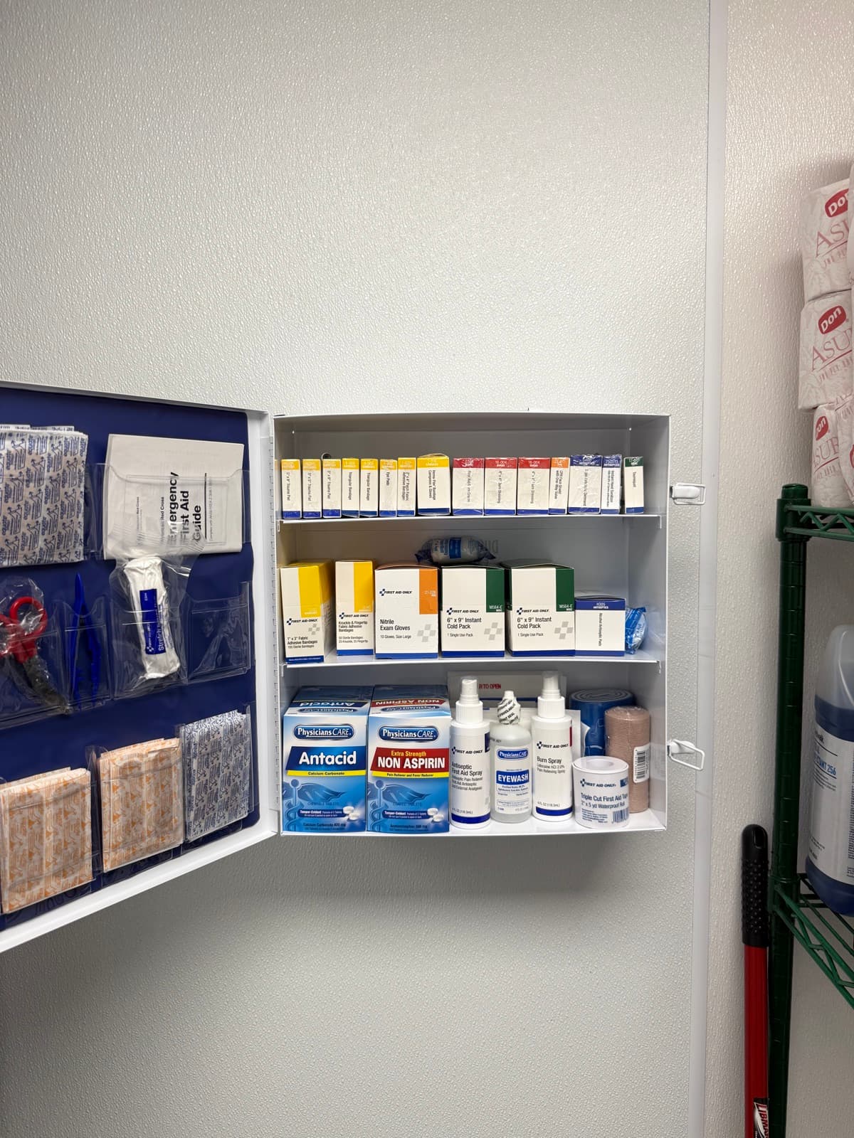 Fully stocked first aid cabinet with bandages, cold packs, eyewash, and OSHA-compliant supplies