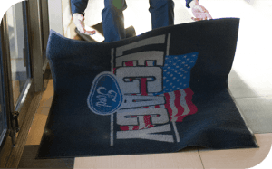 Custom logo entry mat being placed at a business entrance